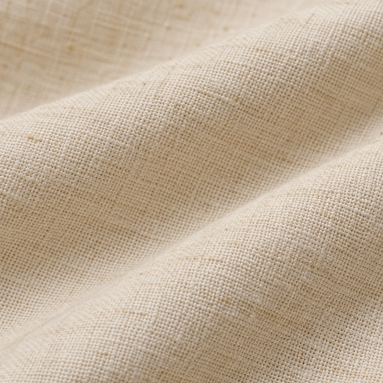 Warm ivory cotton in soft folds, showing its matte plain weave and subtle yarn texture.