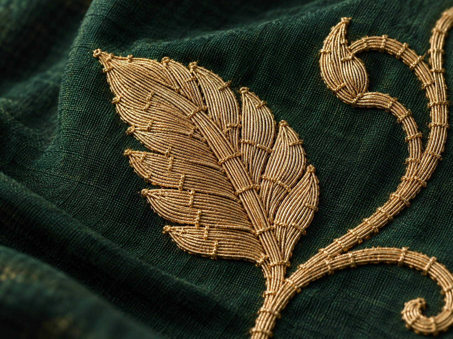 Small binding stitches secure metallic-looking floral ornament to a dark ground.