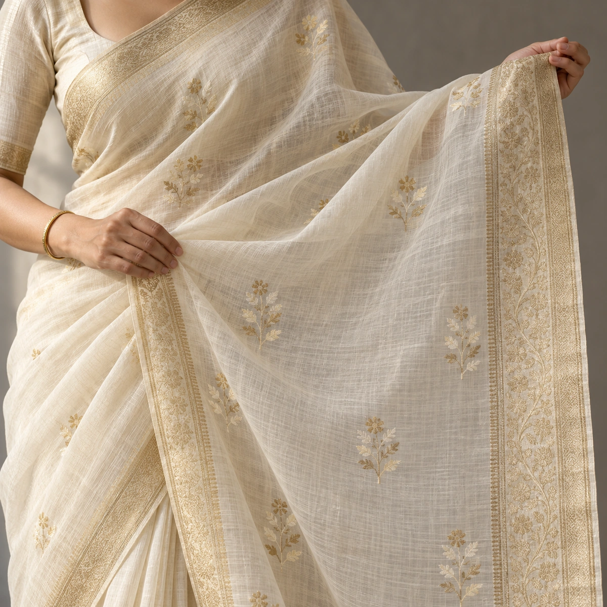 An ivory Jamdani-style saree held open to show small woven floral motifs on a sheer ground