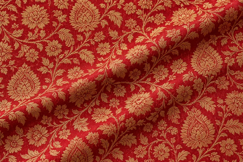 Dense gold-coloured floral patterning covering red fabric.